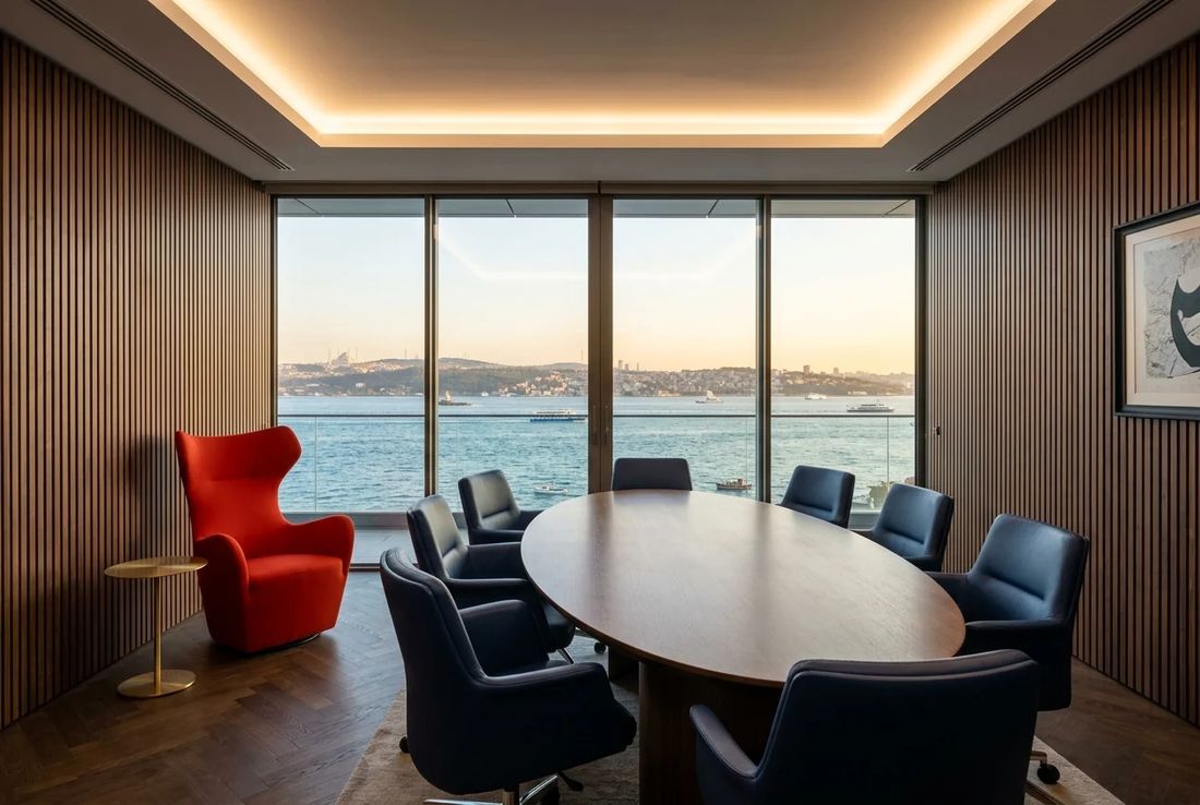Prestigious family law mediation salon with acoustic vertical timber slats, elliptical oak table, Bosphorus views and a red velvet armchair